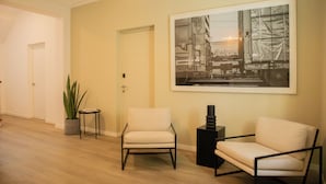 A modern interior with two white armchairs, a large black-and-white photograph on the wall, and a potted plant. - Casa La Paz by Wynwood House (Lima)