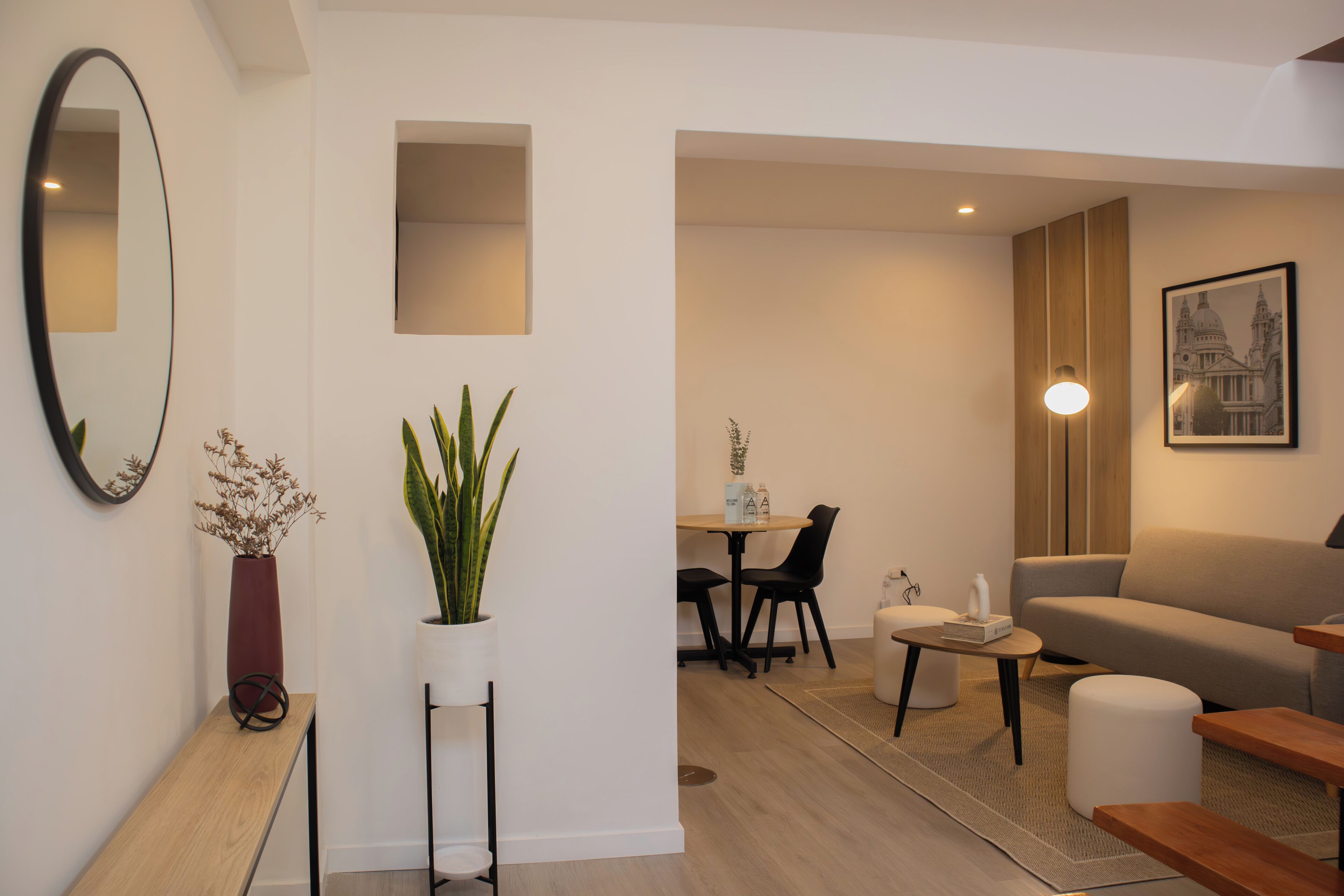 A modern living room with a sofa, a coffee table, and a dining area with chairs and a table.