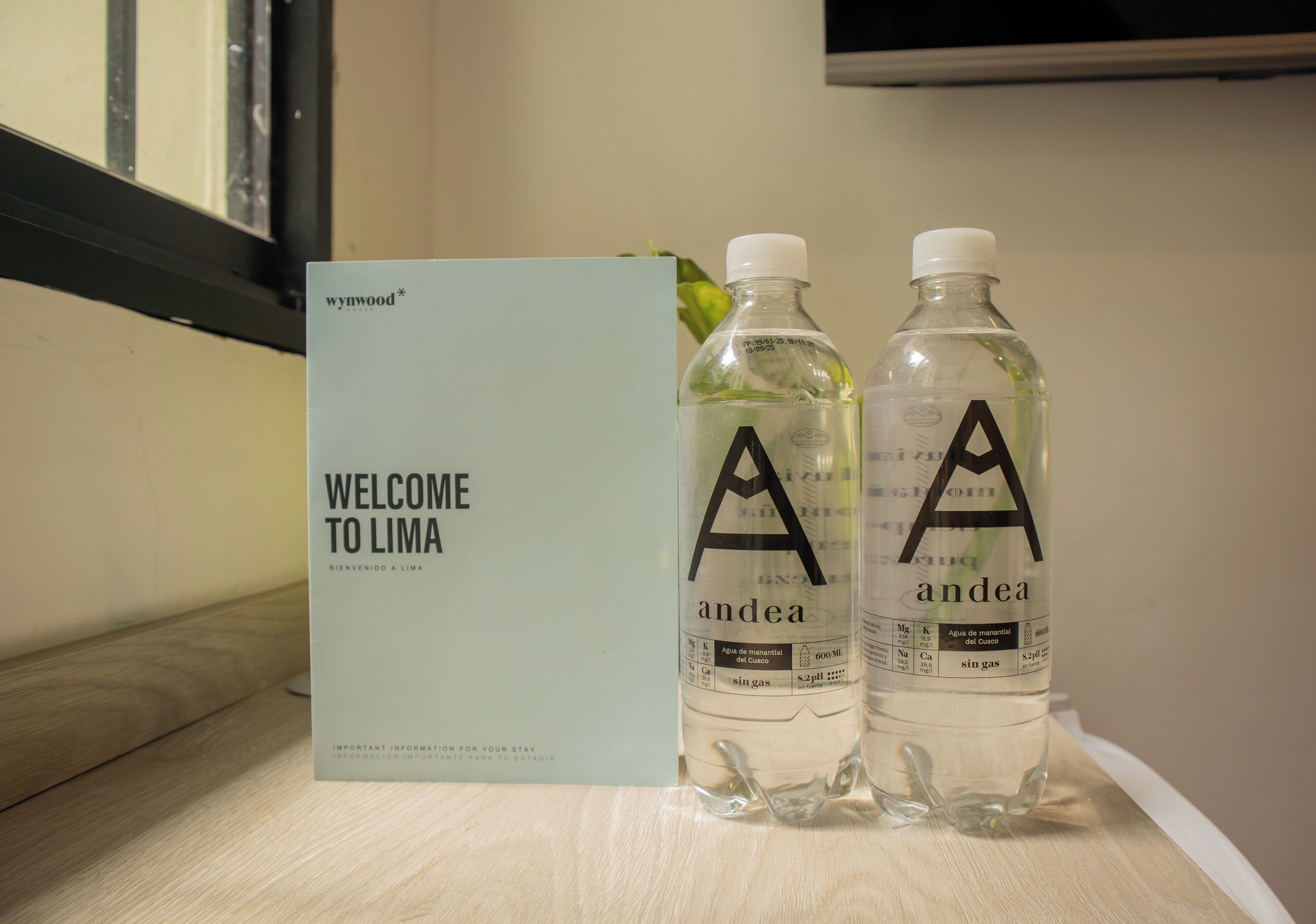 Un letrero de bienvenida y dos botellas de agua con la marca 'andea' sobre una mesa.