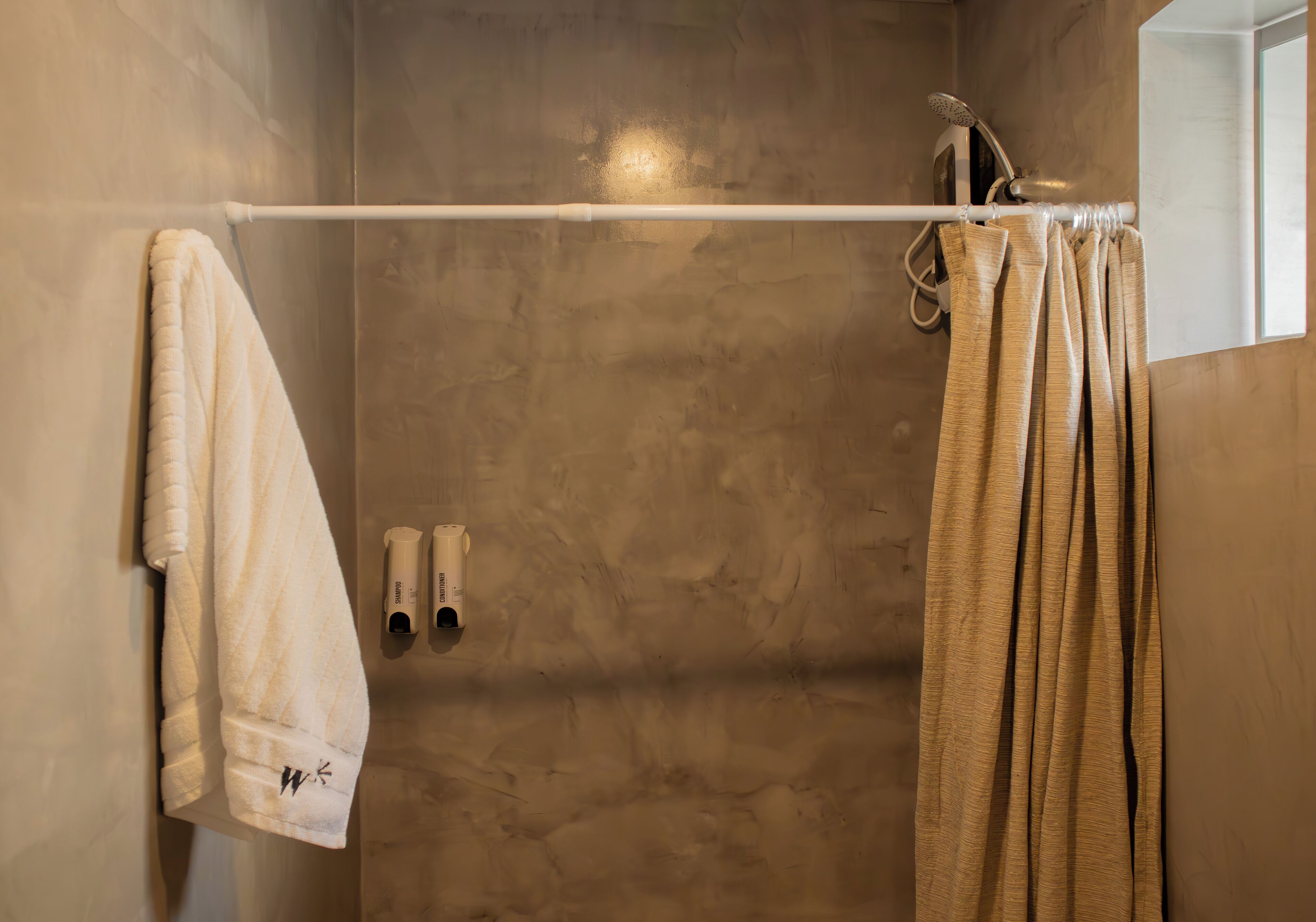 Un baño con toallero, cortina de ducha y dos botellas de champú.