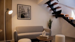 A modern living room with a sofa, a coffee table, a lamp, a staircase, and a framed picture on the wall. - Casa La Paz by Wynwood House (Lima)