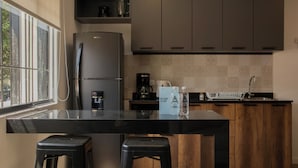 A modern kitchen with a black countertop, stainless steel appliances, wooden cabinets, and a window providing natural light. - Casa La Paz by Wynwood House (Lima)