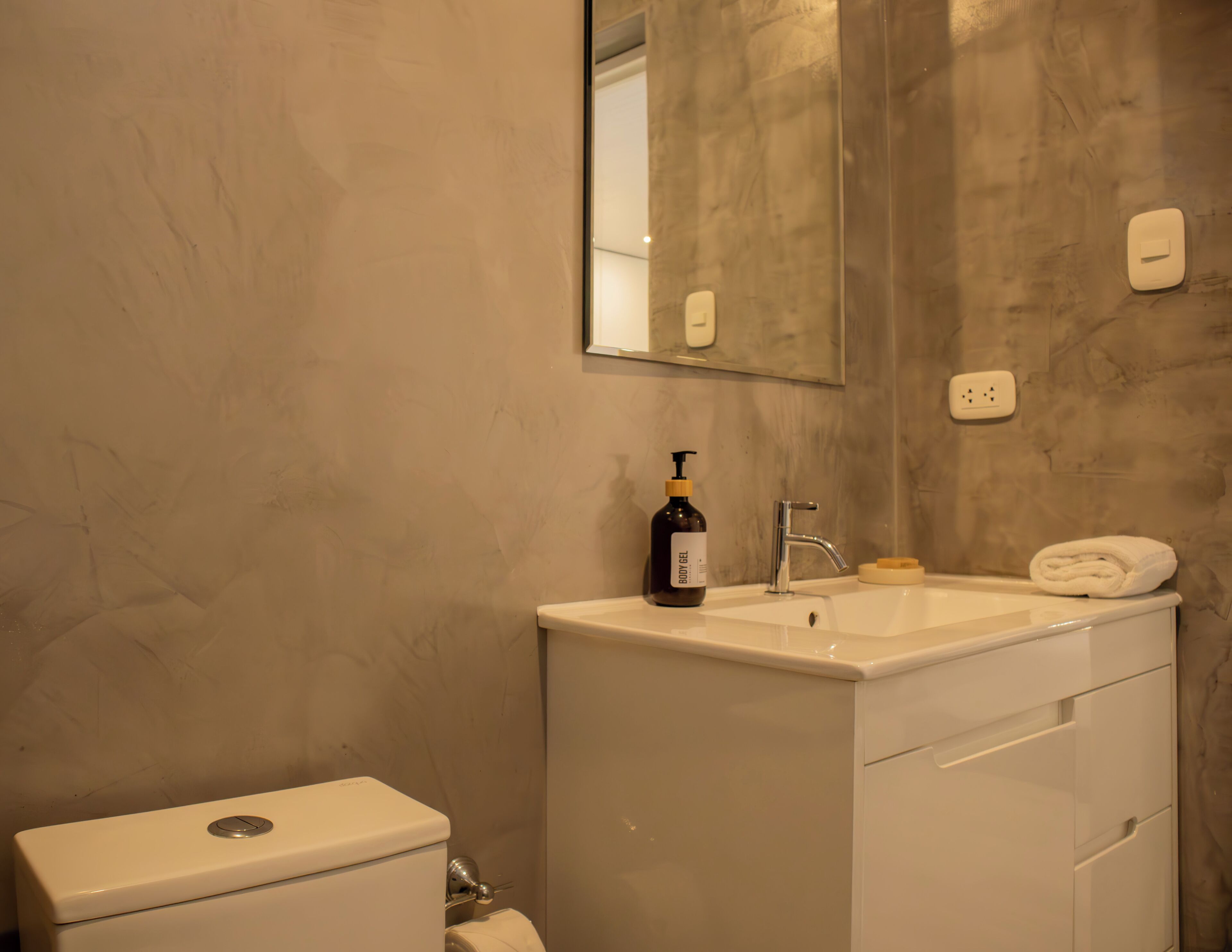 A bathroom with a white sink, a mirror, and a toilet.