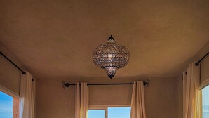 A cozy room with a large window, a patterned rug, and a unique chandelier. - Atlas Horizon Marrakech Auberge and Suites (marrakech)