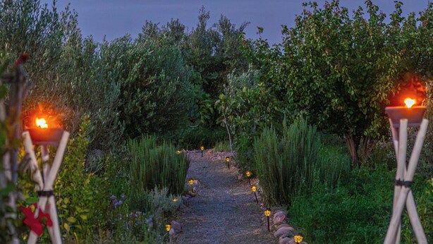 A pathway leading to a beach with a crescent moon in the sky, flanked by greenery and illuminated by small lanterns. - Atlas Horizon Marrakech Auberge and Suites (marrakech)