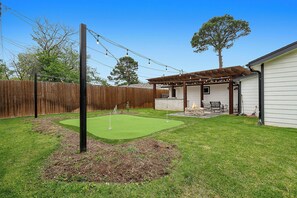 A backyard with a putting green, a fire pit, outdoor furniture, and a wooden fence. - 0.8 Mi to AT&T | Stadium View | Walk to Games (Arlington)
