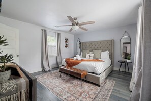 A bedroom with a bed, a ceiling fan, a bedside table, a mirror, and a potted plant. - 0.8 Mi to AT&T | Stadium View | Walk to Games (Arlington)
