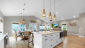 A spacious kitchen with a large island, pendant lighting, and a view to the outside. - Cape San Blas Gulf Views, Private Pool, Steps to Beach (Port St. Joe)
