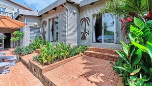 A modern house with a patio area, a palm tree, and various plants.