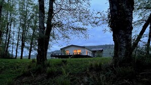 A house with a deck, surrounded by trees and a grassy area.