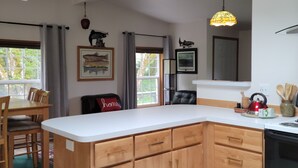 A modern kitchen with wooden cabinets, a white countertop, and a hanging pendant light.