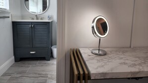 A bathroom with a vanity, a round mirror, and a marble countertop. - Dogs Welcome-Close to Beach-Fenced Yard (Sebastian)