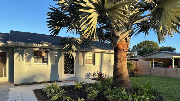 A residential house with a well-maintained lawn, a palm tree, and a garage. - Dogs Welcome-Close to Beach-Fenced Yard (Sebastian)