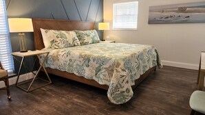 A bedroom with a bed, two bedside tables, a lamp, a chair, and a painting on the wall. - Dogs Welcome-Close to Beach-Fenced Yard (Sebastian)
