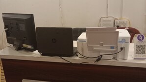 Una reception con una scrivania, un portatile HP, un computer, una stampante e un codice QR sul lato destro.