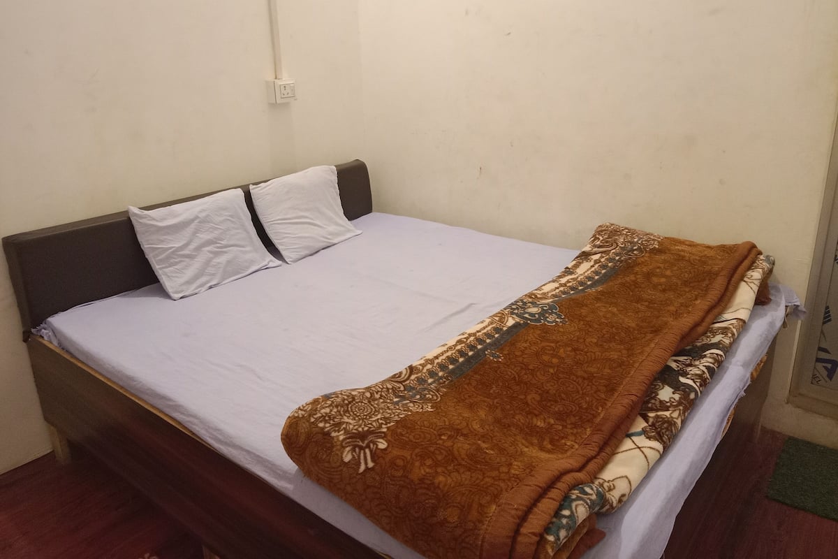 Uma cama de solteiro com colchão branco e manta marrom estampada com flores.