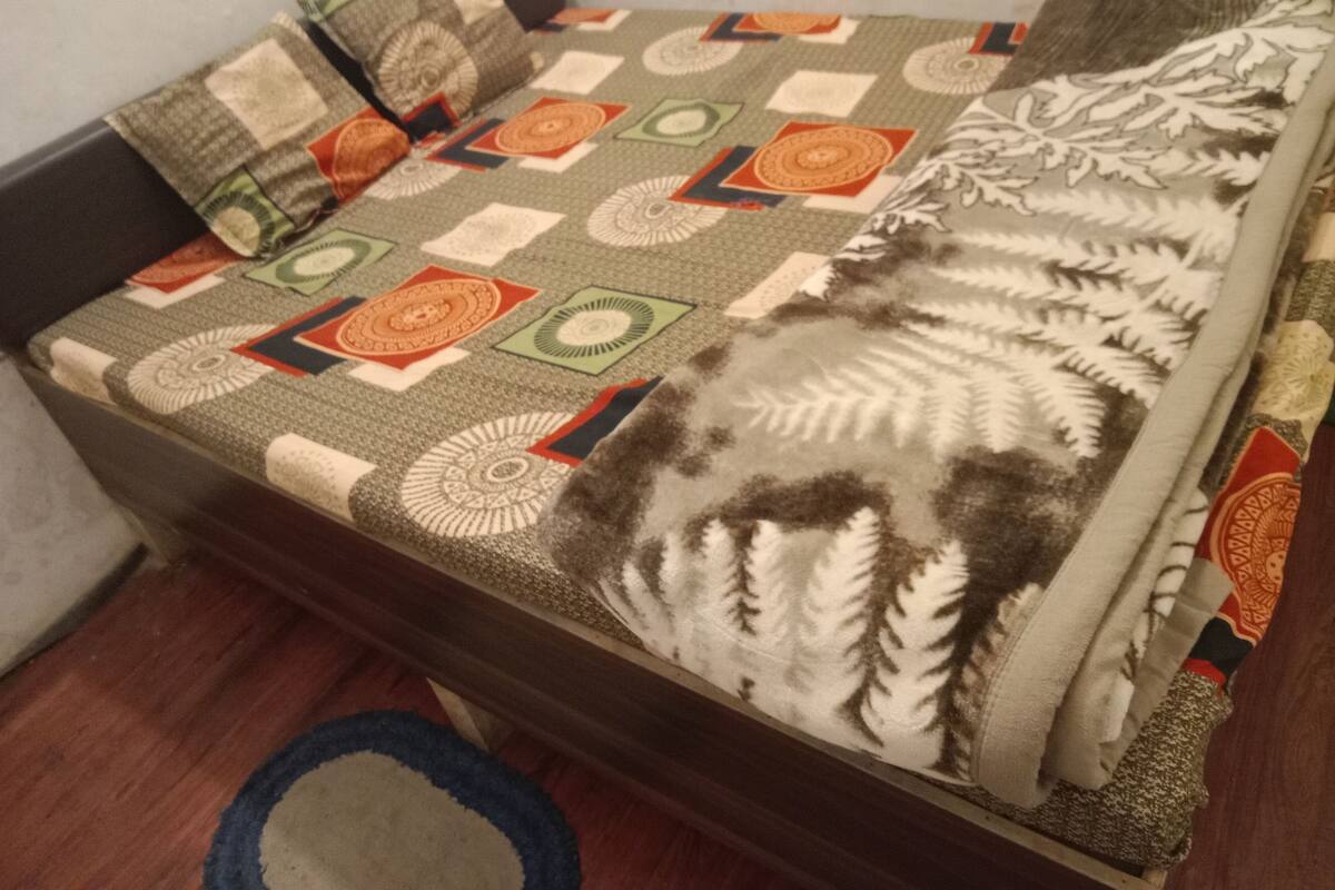 Uma cama com colcha estampada, travesseiros e manta.