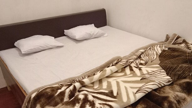 Un letto con una coperta a motivi zebrati, cuscini bianchi e una testiera in legno.