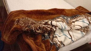 Un letto con lenzuola bianche e una coperta marrone fantasia.