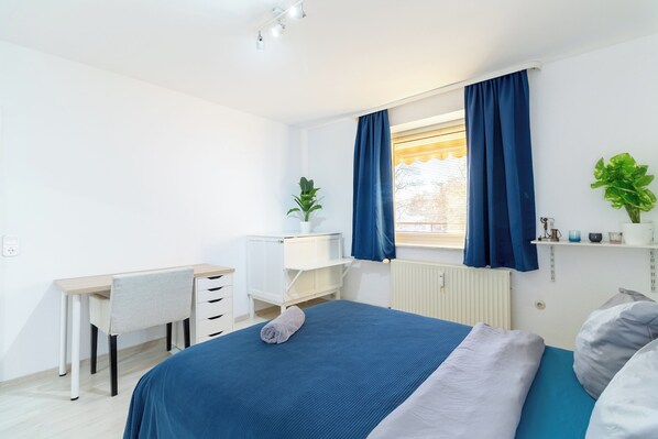 A bedroom with a bed, a desk, and a chair.