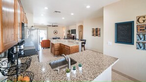 A modern kitchen with granite countertops, a central island, and wooden cabinets. - Cozy 3 bedroom home with private heated pool on a golf course with mountain view (Avondale)