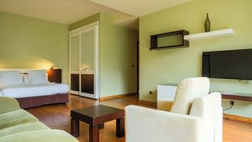 A modern living room with a sofa, a chair, a small table, a bed, and a TV.