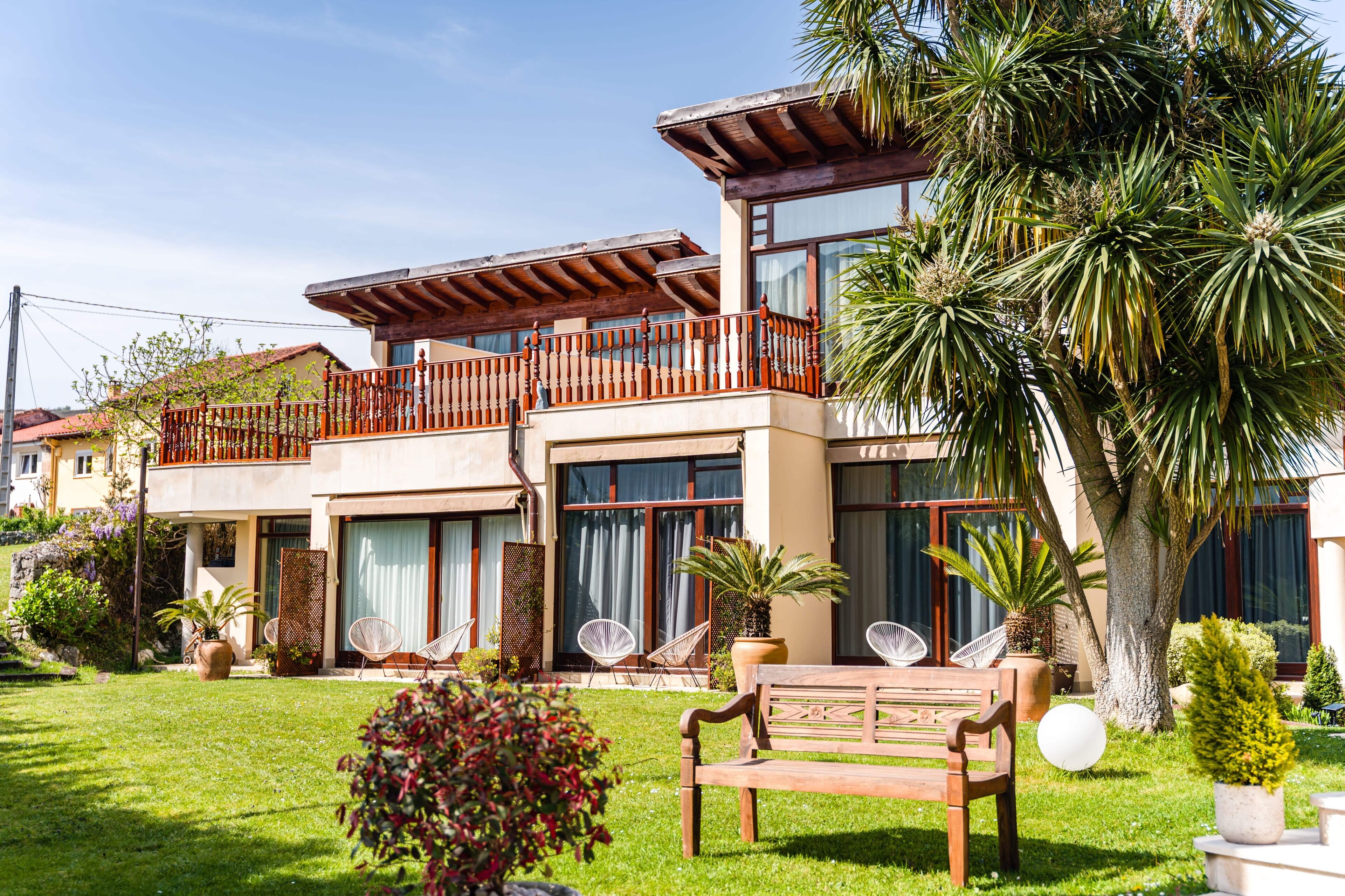 A two-story building with a balcony, potted plants, and outdoor seating.