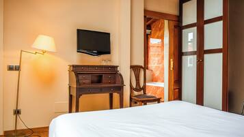 Una habitación de hotel con cama, escritorio, silla, televisor y armario.