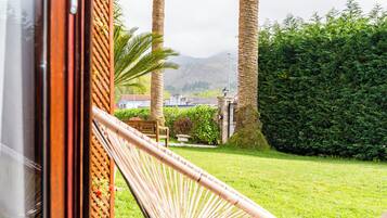 Una poltrona amaca in un giardino rigoglioso con vista su una montagna e un edificio sullo sfondo.