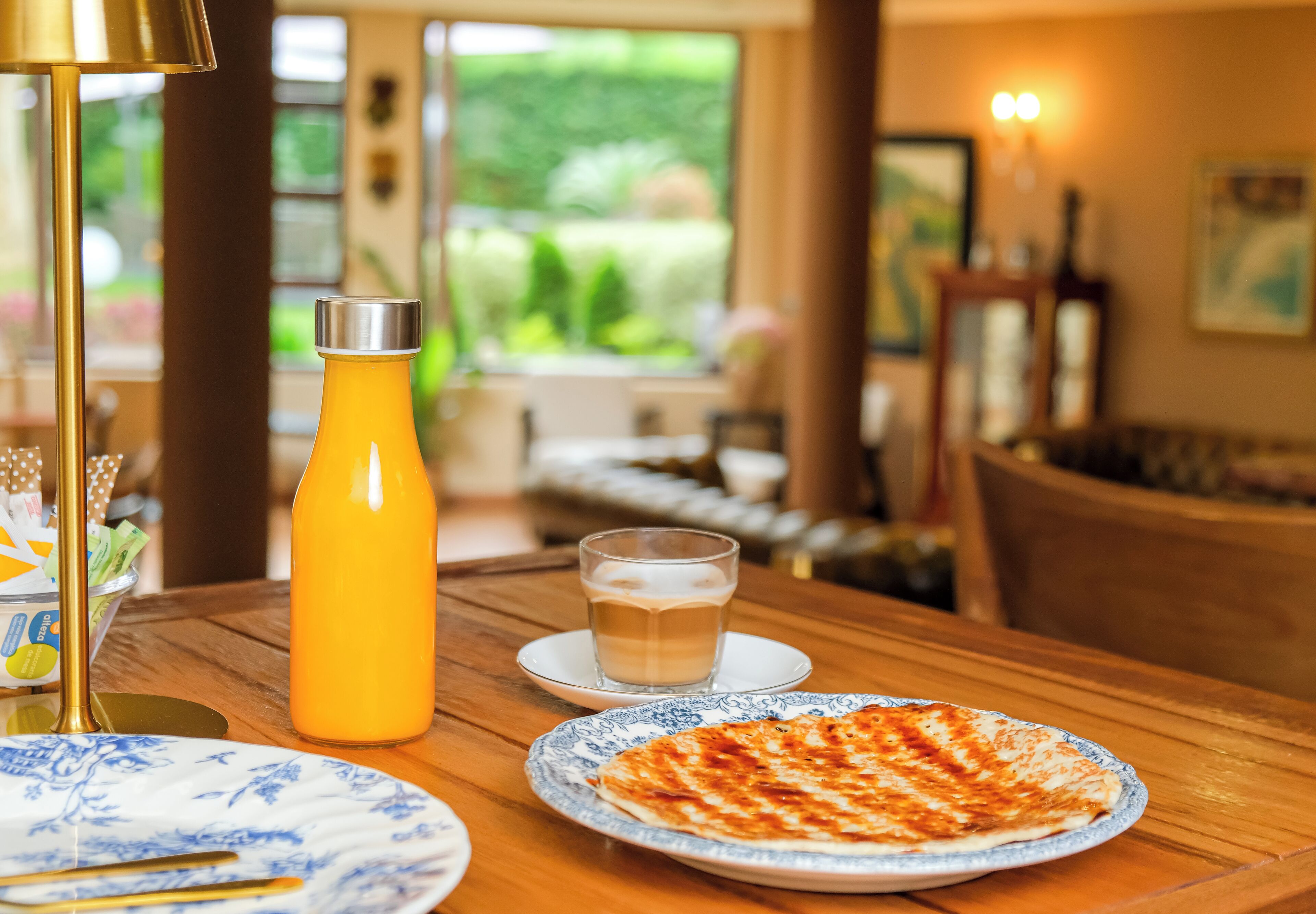 A dining table with a bottle of orange juice, a glass of coffee, and a plate of food.