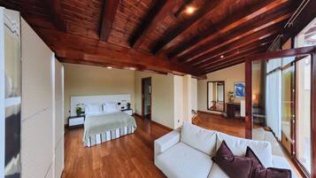 A spacious room with a large bed, a sofa, and a wooden ceiling.