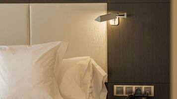 A hotel room with a bed, a bedside lamp, a telephone, and a wall socket.