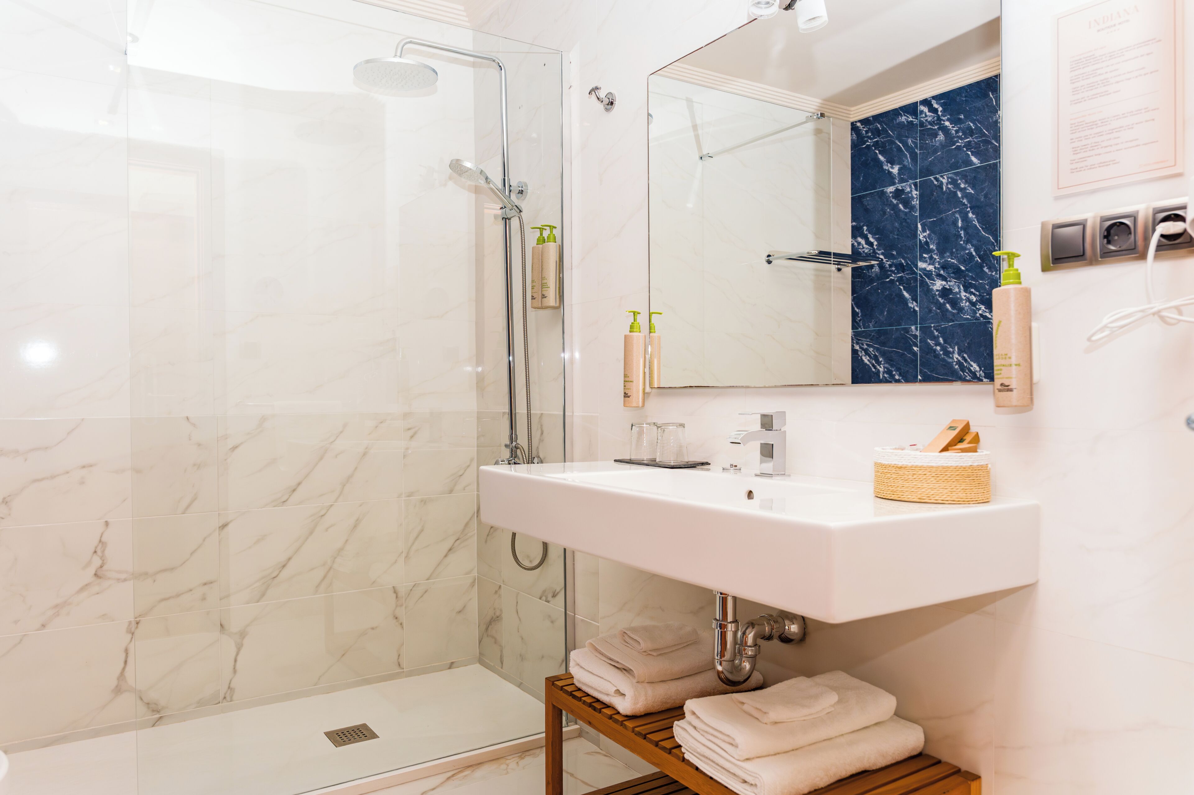 Een badkamer met een douche, een wastafel, een spiegel en een handdoekrek.