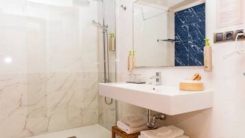 Een badkamer met een douche, een wastafel, een spiegel en een handdoekrek.