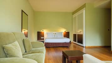 Una habitación de hotel con cama, sofá, mesa de madera y un espejo grande.