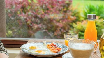 A breakfast table with eggs, toast, and juice, set against a window with a garden view.