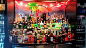 Un bar con varias botellas de alcohol, un letrero de neón y una decoración con palmera.
