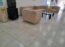 Un amplio salón con un sofá seccional color beige, un mueble multimedia negro y un dispensador de agua.