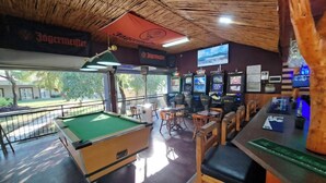 Una sala de billar con mesa de pool, zona de bar y varias máquinas de juego.