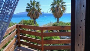 Una terrassa de fusta amb barana, palmeres i vista a l'oceà.