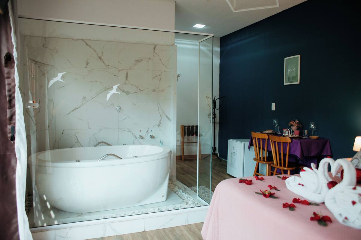 A modern bathroom with a freestanding bathtub, a glass shower enclosure, and a dining area with a table set for two.