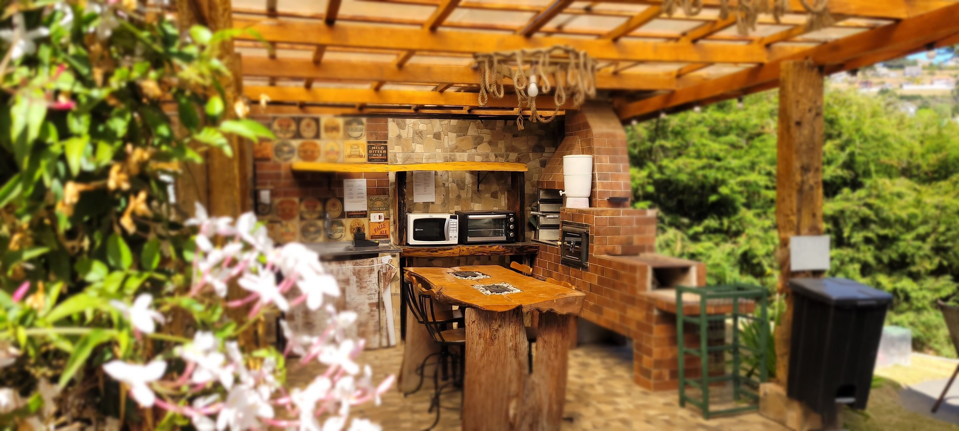 Eine Außenküche mit Backsteinwänden, Holztischen und einer Pergola.