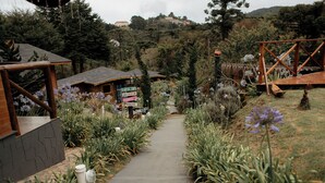 A pathway lined with plants and a wooden structure on the right. - Pousada Chalés da Mantiqueira (Campos do Jordão)