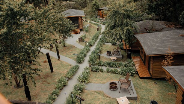A wooden cabin with a paved path leading to it, surrounded by dense greenery. - Pousada Chalés da Mantiqueira (Campos do Jordão)