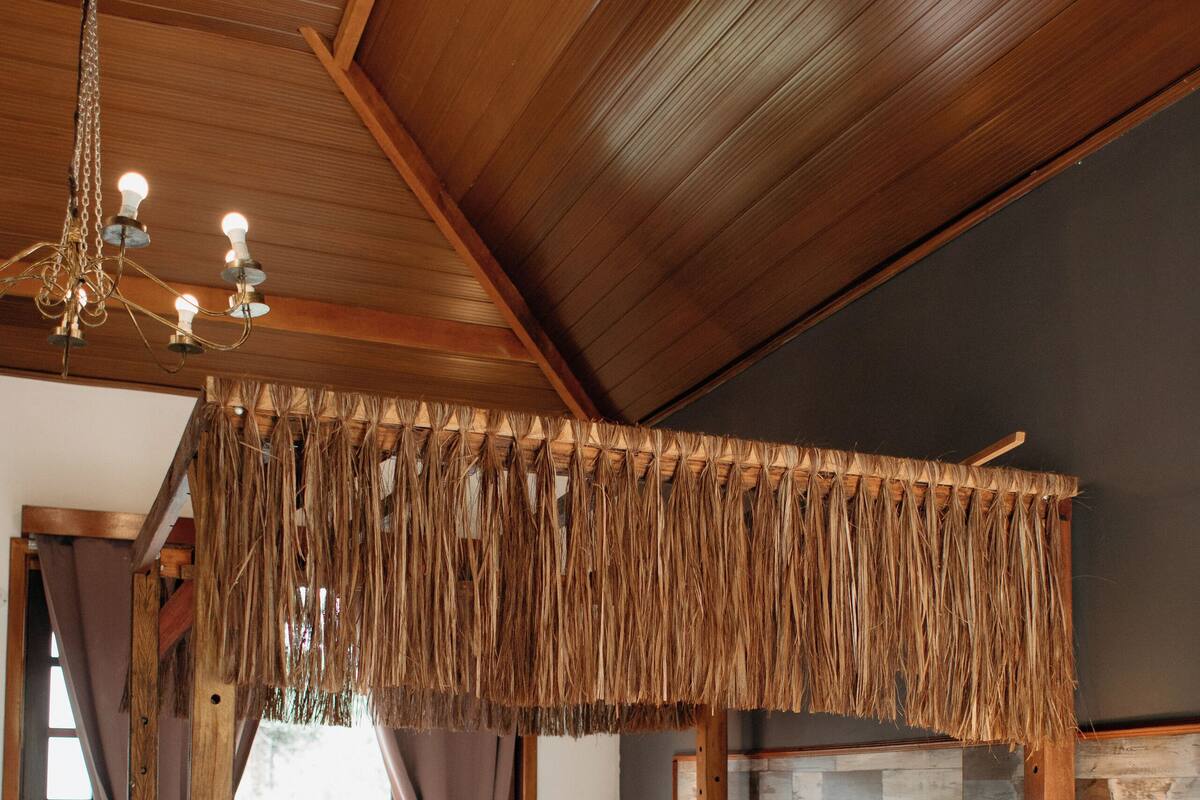 A bedroom with a canopy bed, wooden ceiling, and a stone accent wall.