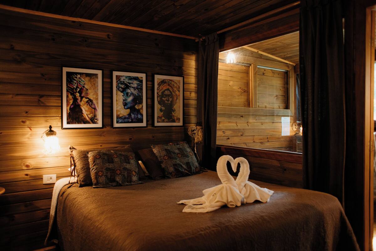 A wooden cabin-style bedroom with a bed, pillows, and wall-mounted artwork.