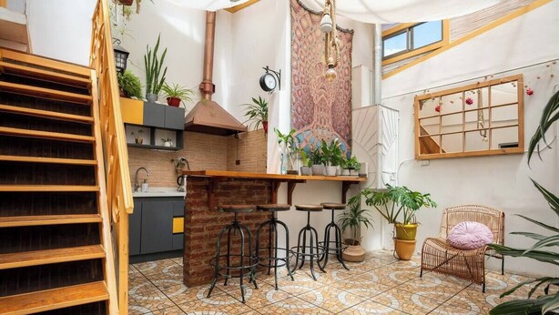 A cozy kitchen with a brick wall, wooden bar stools, and a hanging light fixture. - Hostal Casa Fibonacci (Valparaíso)