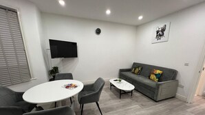 En moderne stue med en grå sofa, et hvidt sofabord og et rundt spisebord med fire stole.