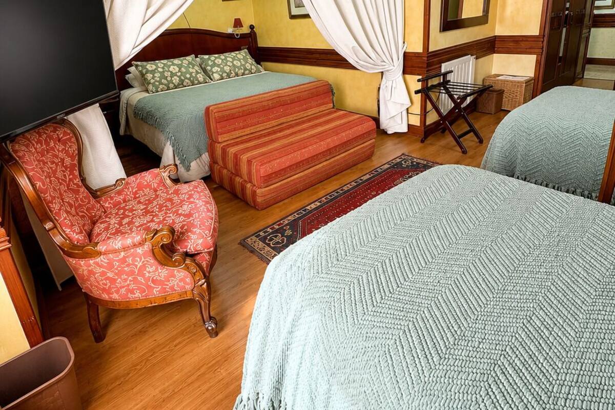 A hotel room with a bed, two bedside tables, a chair, a TV, and a wardrobe.