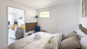 Une chambre à coucher comprenant un lit, une chaise, une fenêtre et une porte donnant sur une autre pièce.